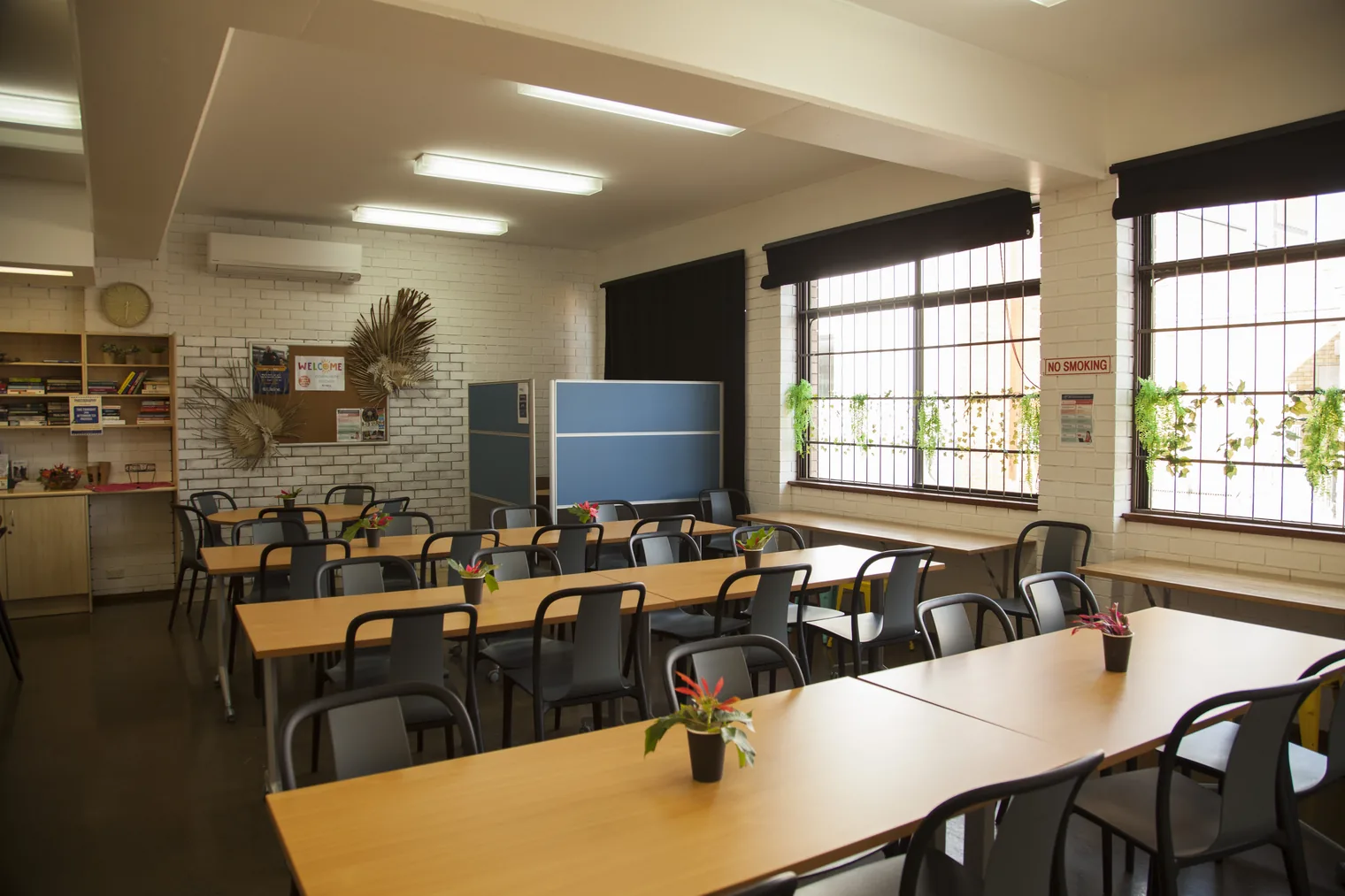 The Lifeline South Coast Community Kitchen dining room, with timber tables and chairs set out and pot plants on the tables