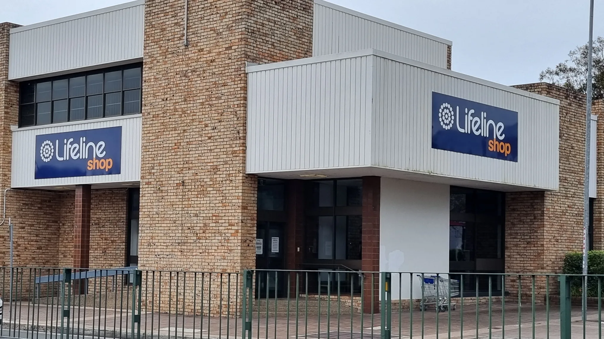 The Lifeline Dapto Shop seen from the street, a two-storey brick corner building with a Lifeline Shop sign on each street frontage