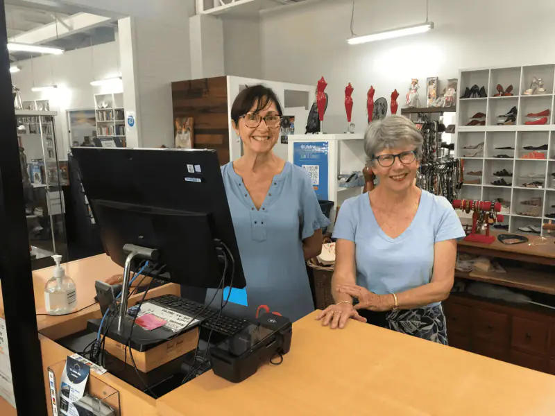 Two Lifeline Shop volunteers behind the counter of a Lifeline Shop