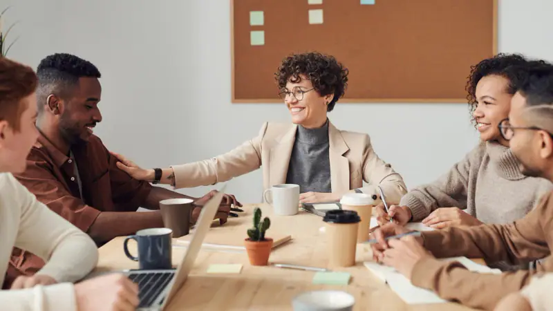 Colleagues talking around a meeting table in an office