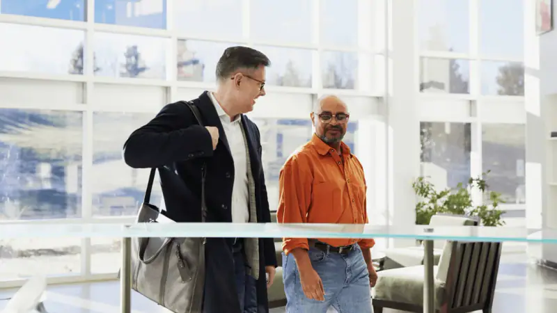 Two colleagues walking and talking through a bright workplace foyer